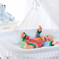 baby laying in a white bassinet