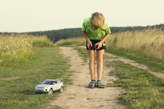 kid playing with a remote control car outside