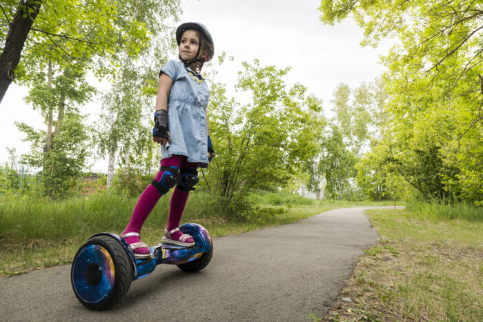 Little girl standing on hoverboard in park