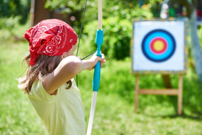 Girl in red bandana shooting a bow