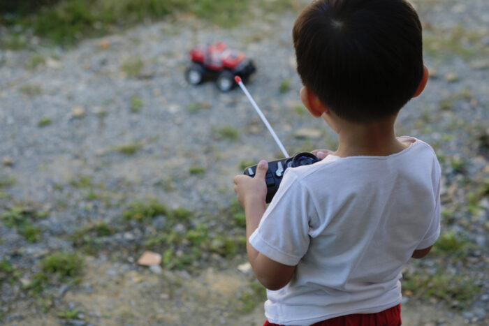 Little boy playing with remote controlled car outside