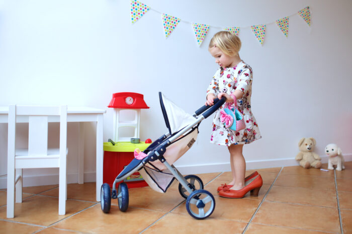 Little girl in high heels with baby stroller