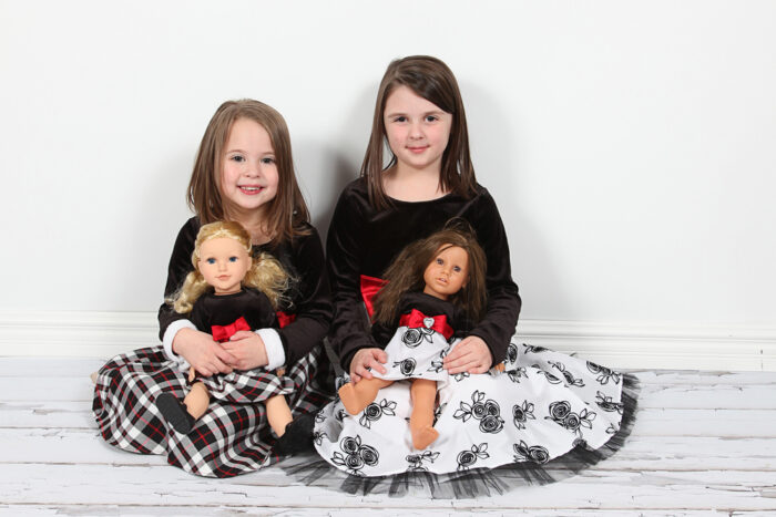 Two sisters pose with their dolls