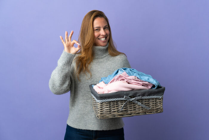 Mom giving the okay sign with basket of laundry